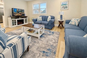 A living room with a fireplace, a television, and a large window.