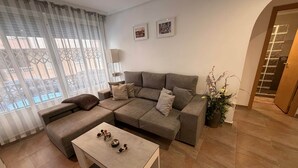 Ein modernes Wohnzimmer mit einem Ecksofa, einem Couchtisch und einer Topfpflanze.