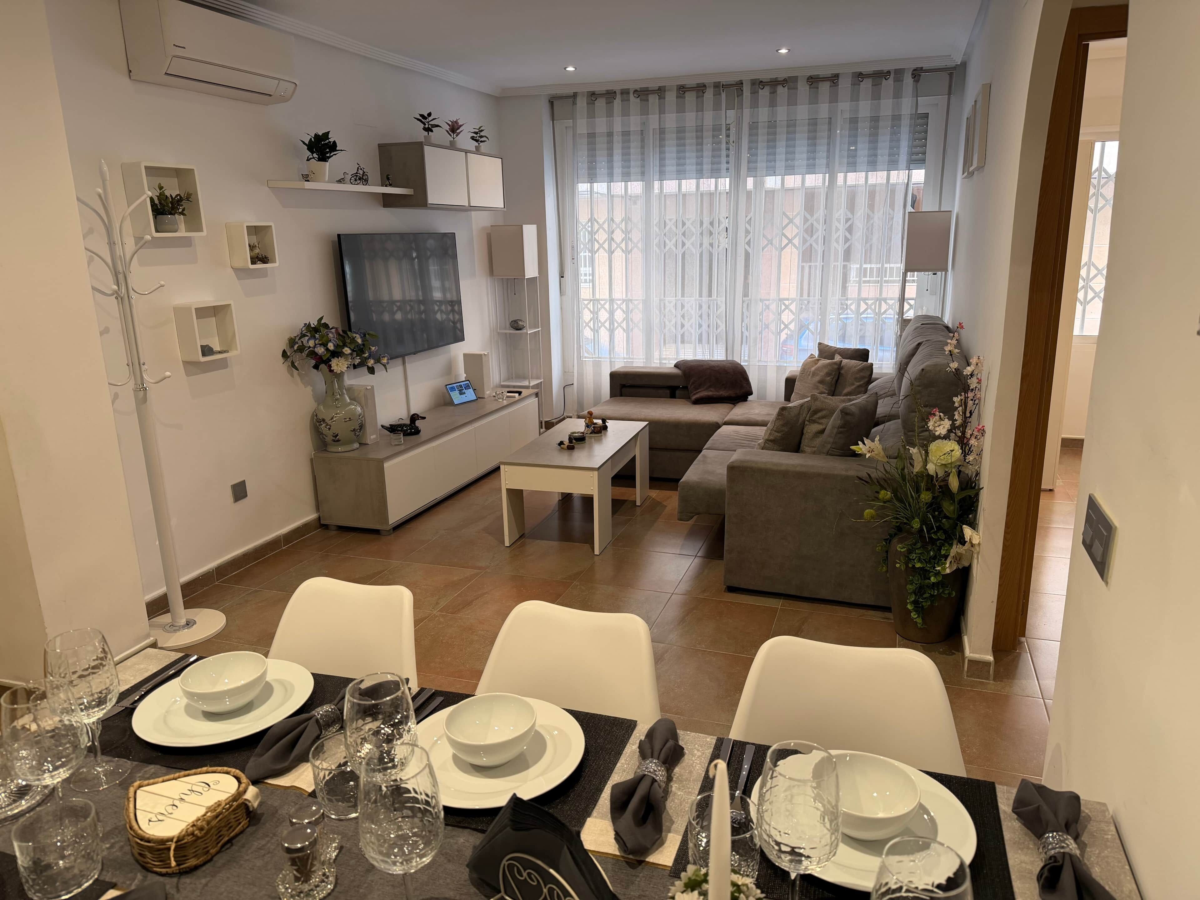 A modern living room with a sofa, TV, and dining area set up for a meal.