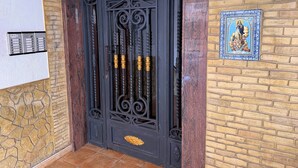 Eine schwarze, verzierte Tür mit der Zahl 8 und einem Zahlenschloss, eine dekorative Wandplatte sowie eine Mauer mit geometrischem Muster.