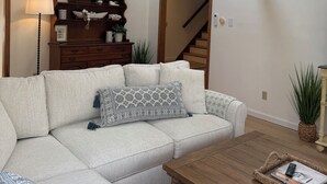 Un salon avec un canapé, une table basse et un escalier.