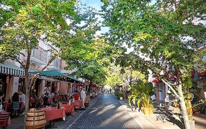 Una calle adoquinada bordeada por terrazas y edificios de arquitectura tradicional.