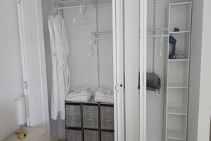 A walk-in closet with hanging robes, folded towels, and open shelves. - Stylish 3BR in MiMo · Minutes to Design District & Wynwood · Free Parking (Miami)