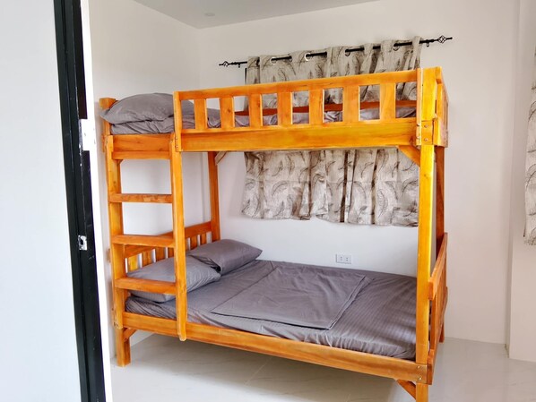 A bunk bed with a ladder, a curtain, and a power outlet on the wall.