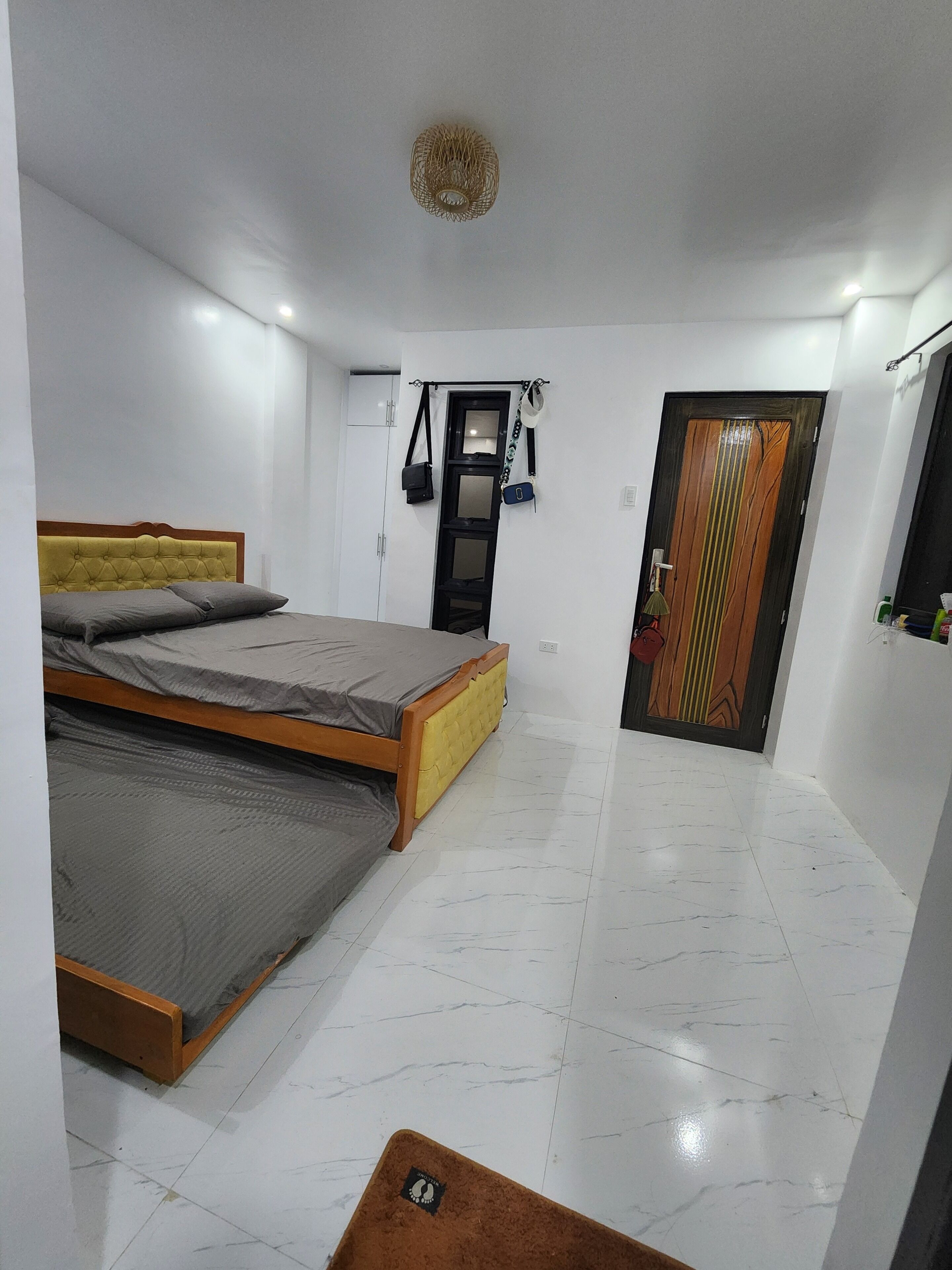 A bedroom with a bed, a wardrobe, a door, and a ceiling light fixture.