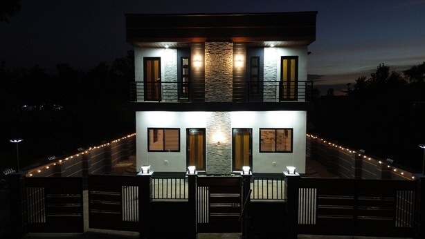 A two-story modern building with a stone facade, multiple balconies, and a gated entrance.