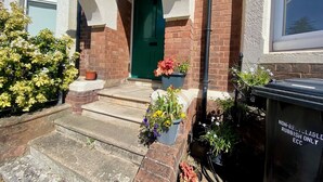 Une maison avec une porte verte, des marches en pierre et des plantes en pot.