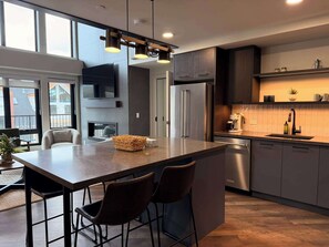 Eine moderne Küche mit einer großen Kochinsel, Barhocker, einem Backofen und einer Kaffeemaschine.