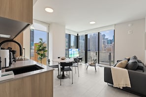 Una cocina moderna con comedor, sofá y ventanas amplias con vista a la ciudad.