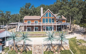 Une maison à deux étages avec un balcon, des fondations en pierre et des palmiers.