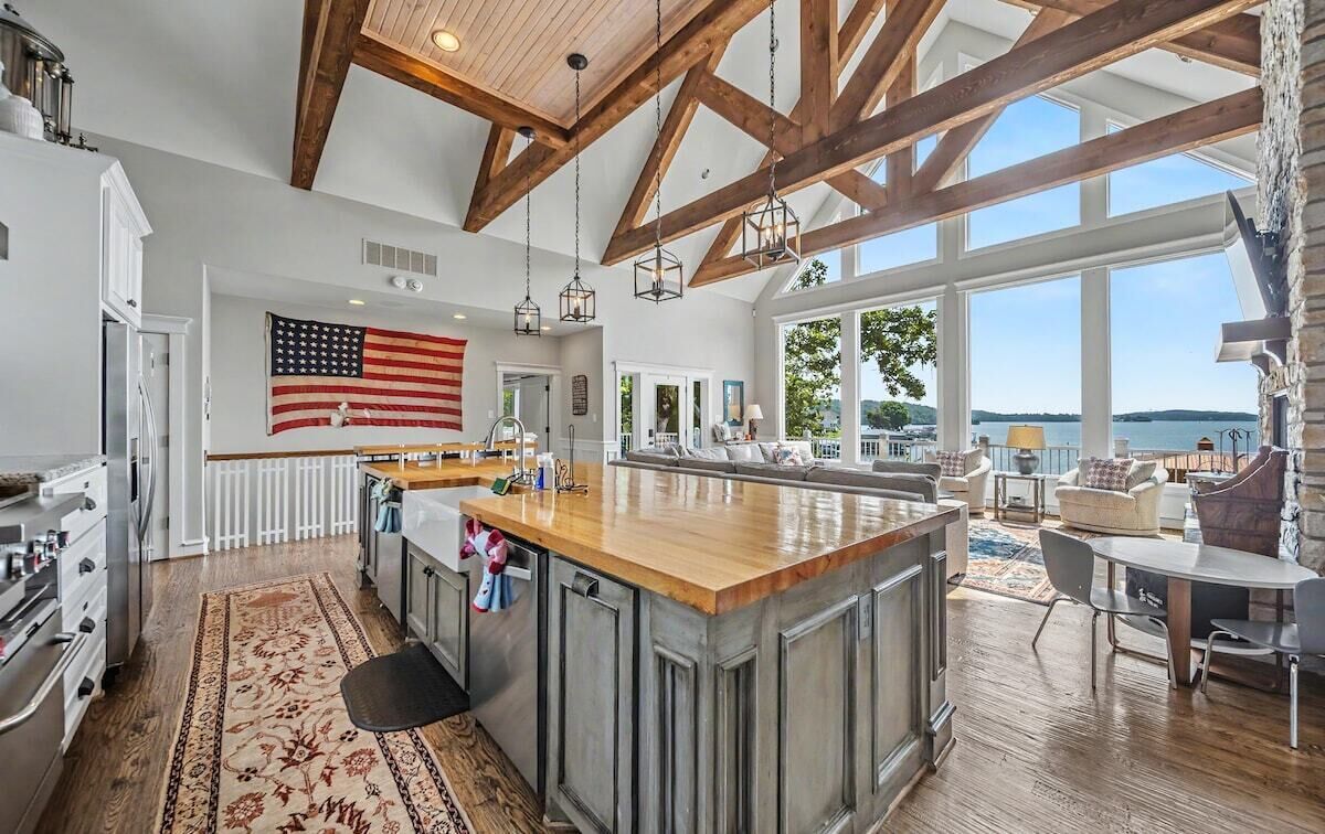 A spacious kitchen with a large island, wooden beams, and a view of the outdoors.