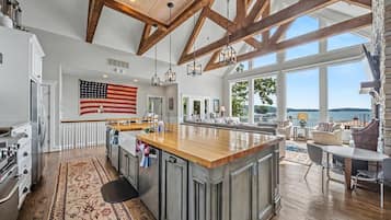 A spacious kitchen with a large island, wooden beams, and a view of the outdoors.