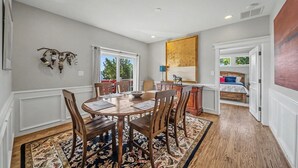 A dining area with a wooden table and chairs, a patterned rug, and a view of the outdoors through a window. - Honeysuckle House (Gravois Mills)