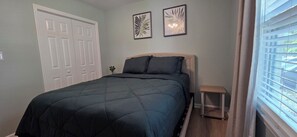 A bedroom with a bed, a bedside table, a door, and two framed pictures on the wall.