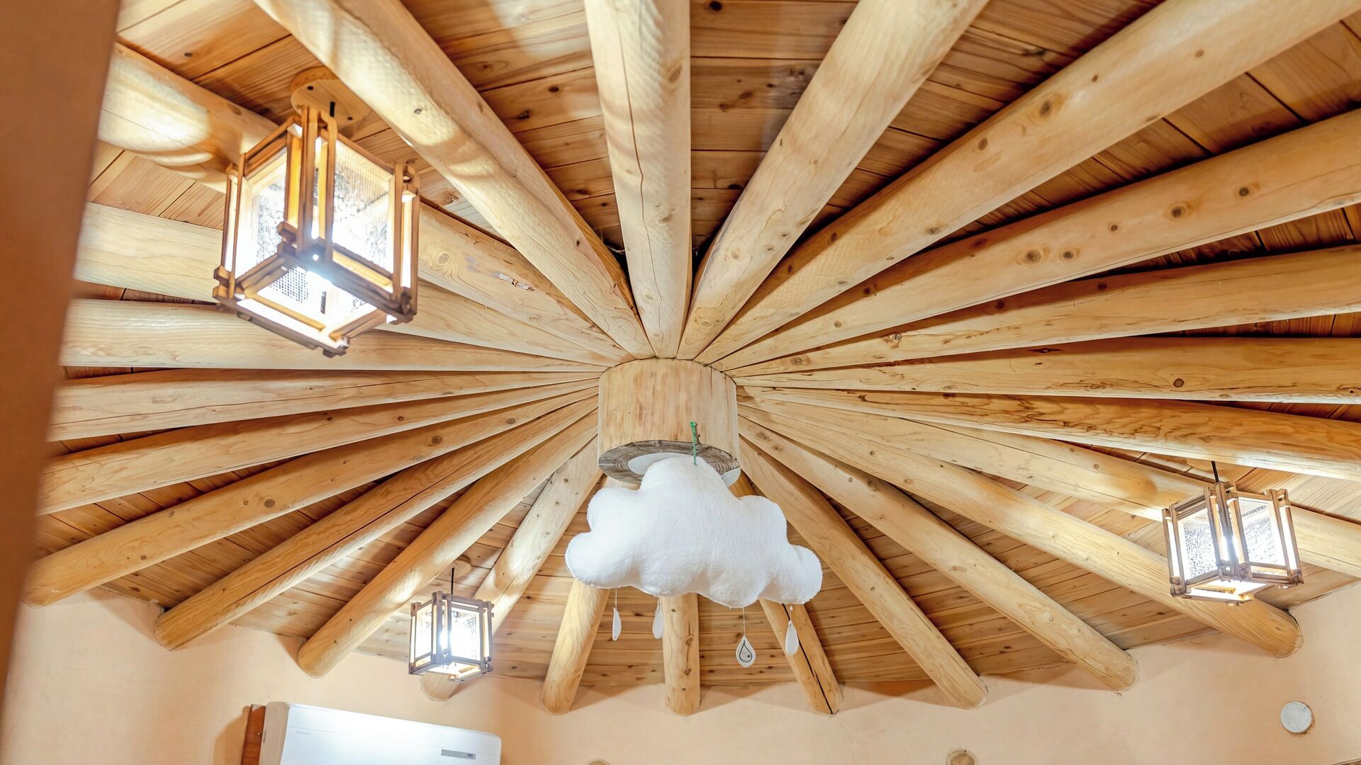 A room with a wooden ceiling, wooden beams, and hanging lantern-style lights.