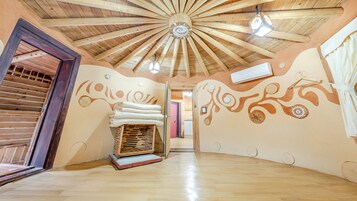 Una habitación con techo de madera, una cama con sábanas blancas y un banco de madera.