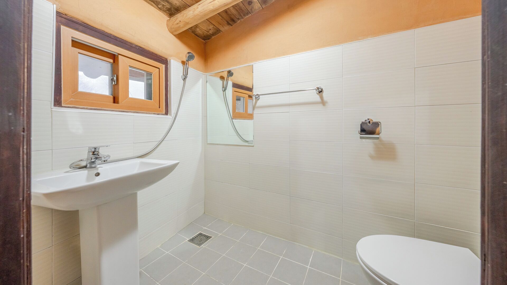 Un baño con lavamanos, inodoro, ducha y toallero.