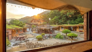 A rustic village scene with traditional buildings, a wooden fence, and a clear view of the surrounding landscape. - Mungyeong Between Mountains Pet Pension (Mungyeong)