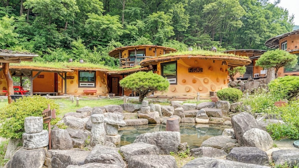 Un tradizionale ryokan giapponese con stanze in tatami, un giardino roccioso e uno stagno con carpe koi.