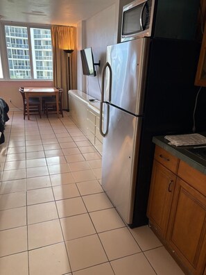 Una cocina equipada con refrigerador, microondas y una mesa de comedor con sillas.