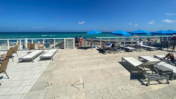 A beachside patio with lounge chairs and umbrellas, overlooking the ocean. - Hotel Sunny Isles (Sunny Isles Beach)