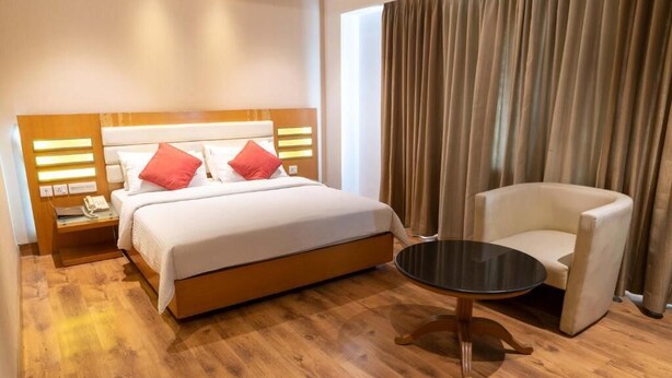 Una camera d'albergo con un letto, un comodino, una sedia e un tavolino.
