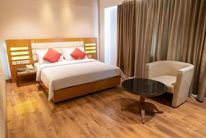 Una habitación de hotel con cama, mesita de noche, silla y una pequeña mesa.
