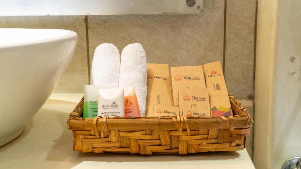 Una cesta de mimbre con artículos de aseo y toallas sobre una encimera de baño.