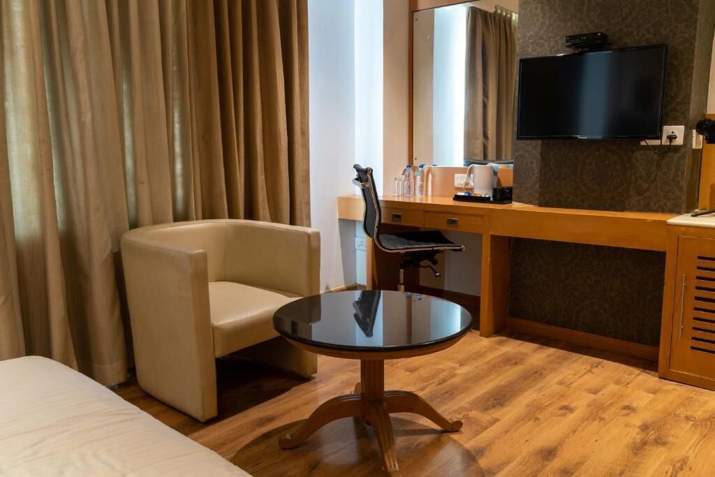 Habitación de hotel con cama, una mesa redonda, una silla, un escritorio con espejo, televisión y armario.