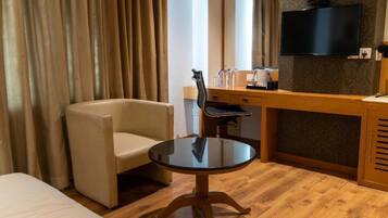 Habitación de hotel con cama, una mesa redonda, una silla, un escritorio con espejo, televisión y armario.