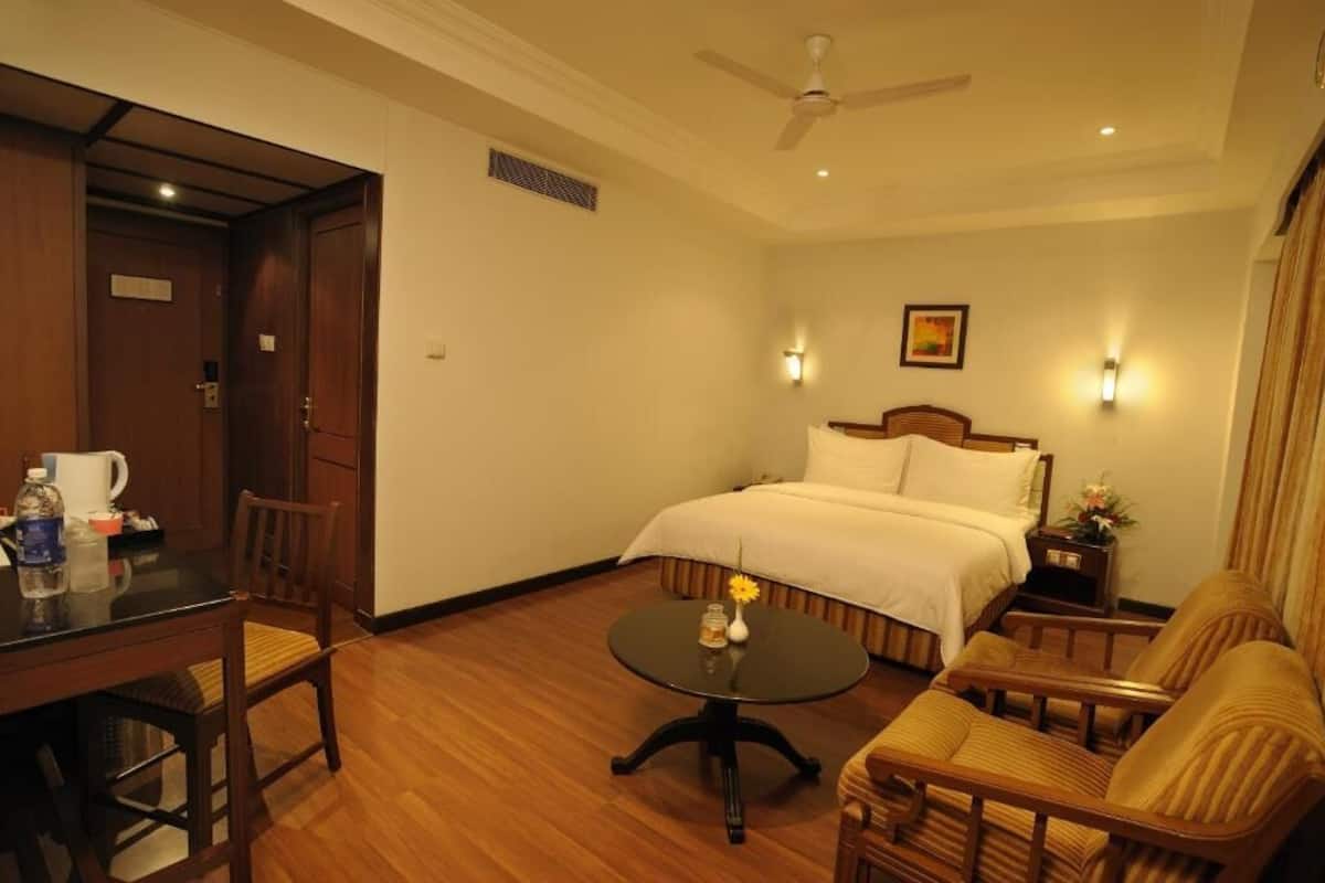 A hotel room with a bed, a dining table, a coffee table, and a sofa.