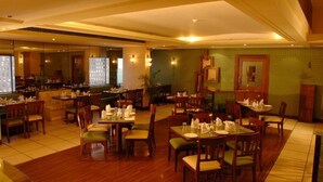 Un ristorante con tavoli e sedie in legno, un'area bar e un muro di mattoni verdi.
