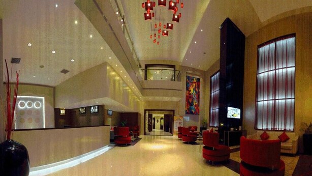 A spacious lobby with a high ceiling, red seating, a reception desk, and a large window with curtains. - HOTEL CAG PRIDE (Coimbatore)