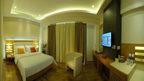 A hotel room with a bed, a desk, a chair, a television, and curtains. - HOTEL CAG PRIDE (Coimbatore)