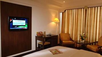 Una habitación de hotel con cama, escritorio con lámpara, televisor y vista a las cortinas.
