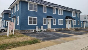 A multi-story blue building with white trim, a signboard, and a parking area. - Beautiful 1-bedroom condo across the street from the beach w/ AC (Brigantine)