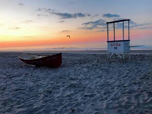 A beach with a lifeguard tower labeled 'LGBA 34' and a red boat. - Beautiful 1-bedroom condo across the street from the beach w/ AC (Brigantine)
