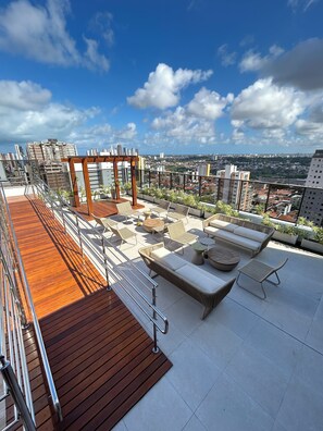 A rooftop terrace with wooden flooring, outdoor seating, and a pergola.