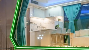 A modern kitchen with white cabinets, a bar area, and a seating space with a sofa and chairs. - Gyeongju Holiday Space Pension (Gyeongju)