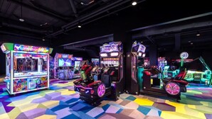 Une salle d’arcade intérieure dotée de différents jeux et d’un sol aux motifs géométriques colorés.