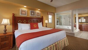 Une chambre d’hôtel avec un grand lit, deux lampes de chevet, un ventilateur de plafond, une salle de bain avec baignoire et vue sur la cuisine.