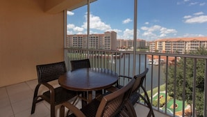 Un balcon avec une table ronde et des chaises, une vue sur un complexe hôtelier et un ciel dégagé.