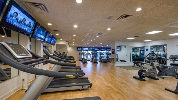 Une salle de sport équipée de tapis de course, de vélos d’exercice et d’appareils de musculation.