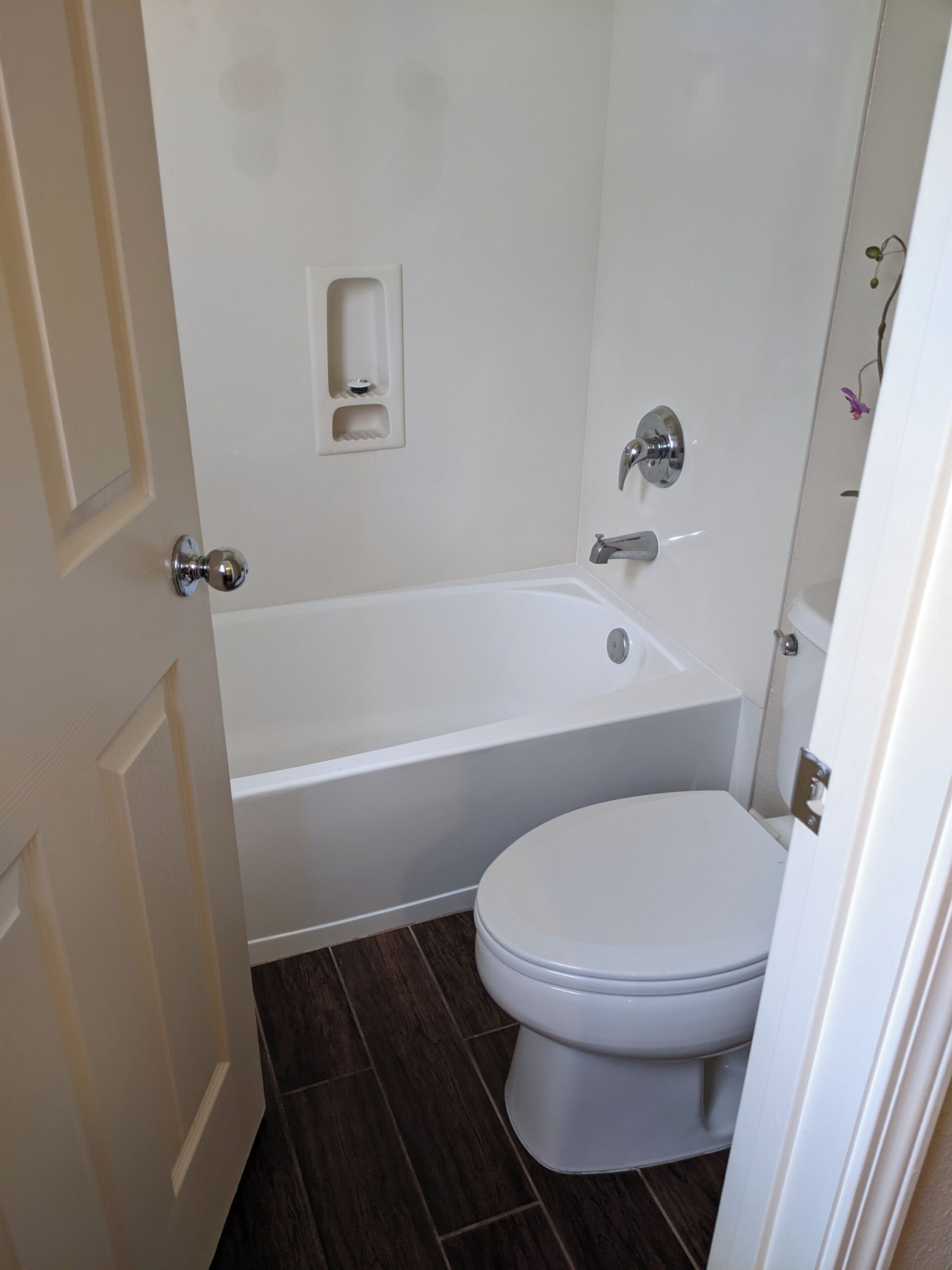 Een badkamer met een bad, toilet en een klein plankje.