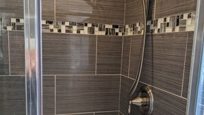 A shower with a handheld showerhead and a wall-mounted faucet. - Executive home close to Keller Beach & Point Pinol shoreline extended stay (Richmond)
