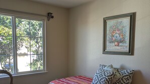 A bedroom with a bed, a chair, a window, and a painting on the wall. - Executive home close to Keller Beach & Point Pinol shoreline extended stay (Richmond)