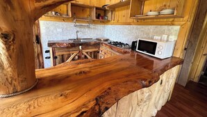 A rustic kitchen with wooden cabinetry, a built-in stove, and a microwave on a wooden countertop. - Secluded mountain cabin: steps to hot spring, river ,& lake (Futrono)