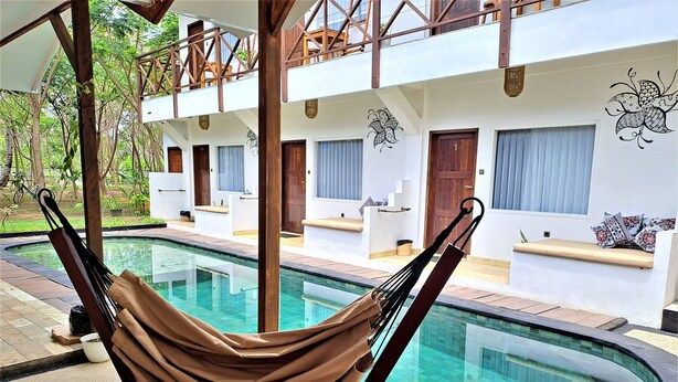 A hammock by a pool with a building in the background. - Katara Gili Boutique Rooms and Bungalows (Gili Trawangan)