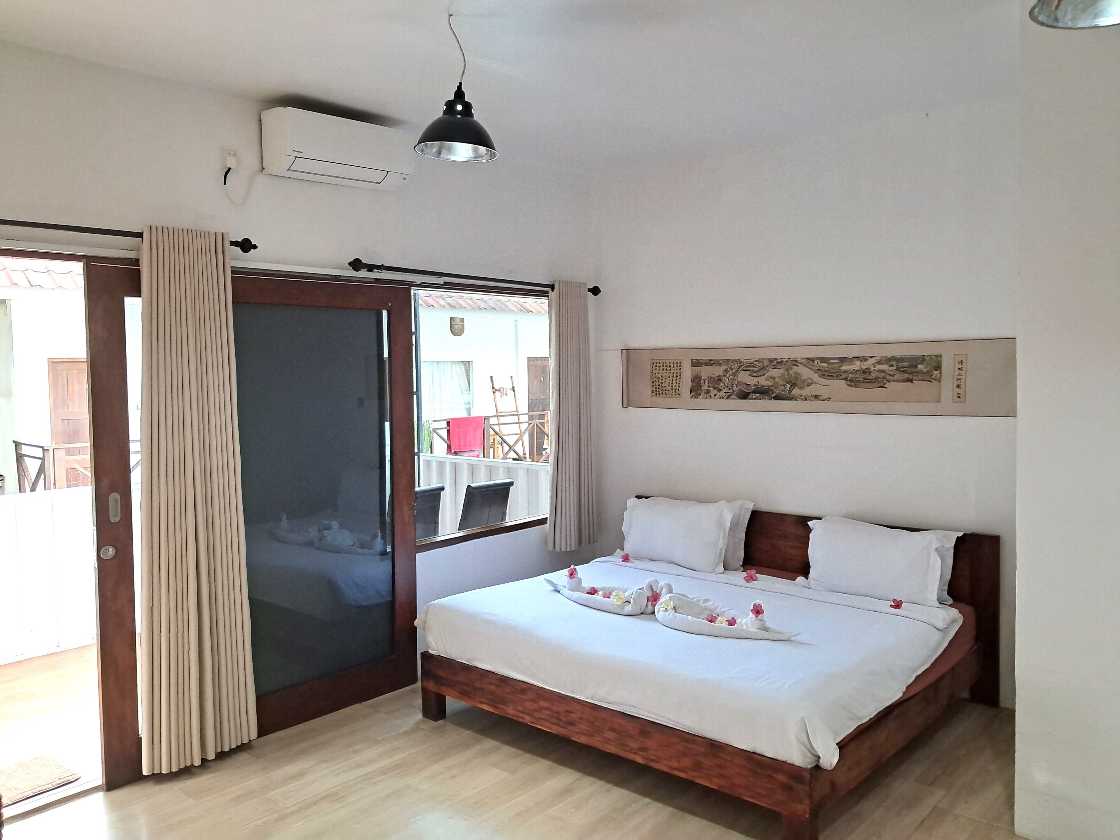 Un dormitorio con cama, puerta corrediza de vidrio, ventilador de techo y aire acondicionado de pared.