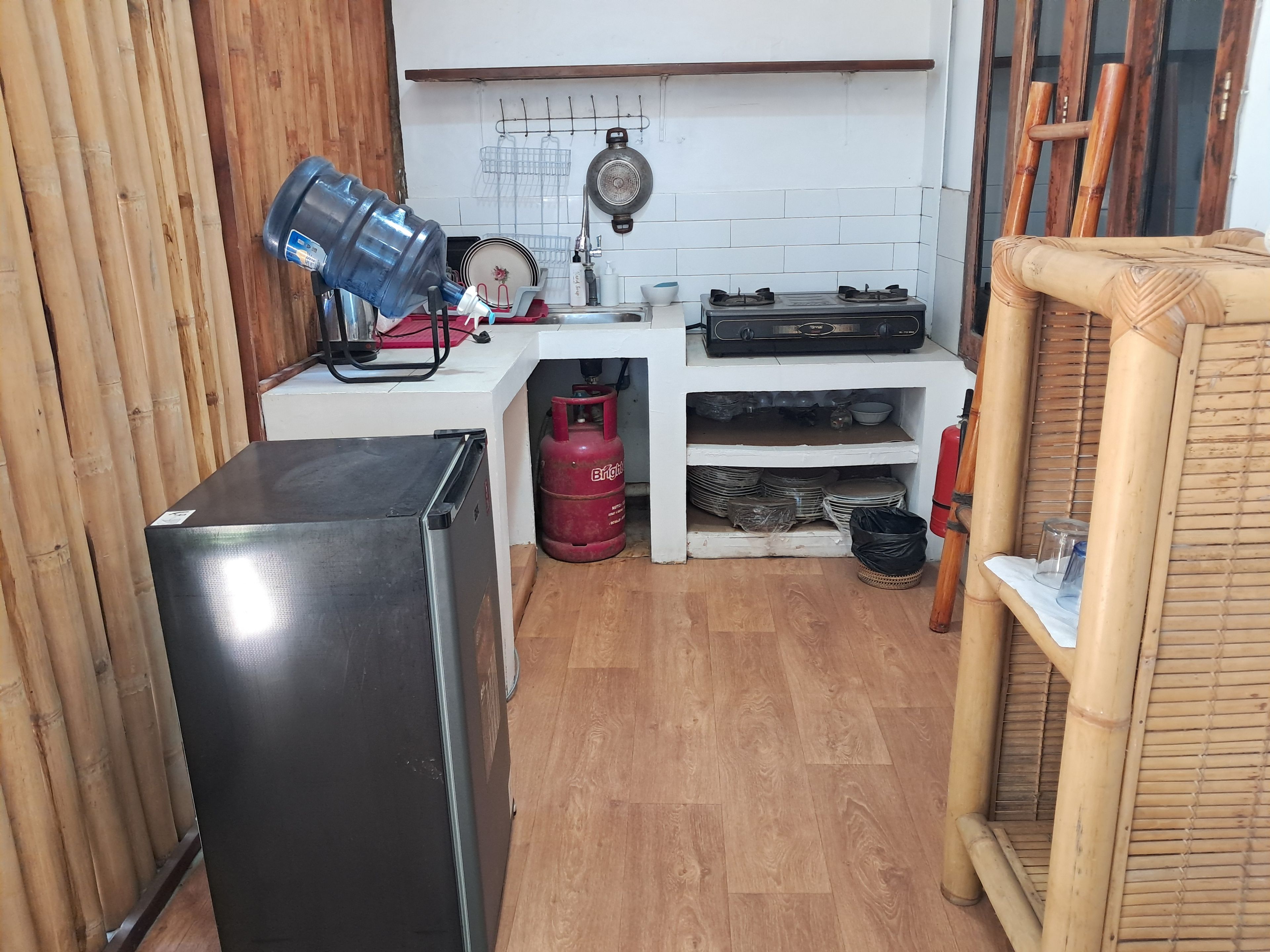 Een kleine keuken met een koelkast, gasfles en gasfornuis.